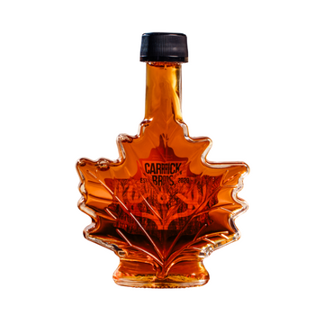 Maple syrup bottle shaped like a leaf with 'Carrick' branding on a white background